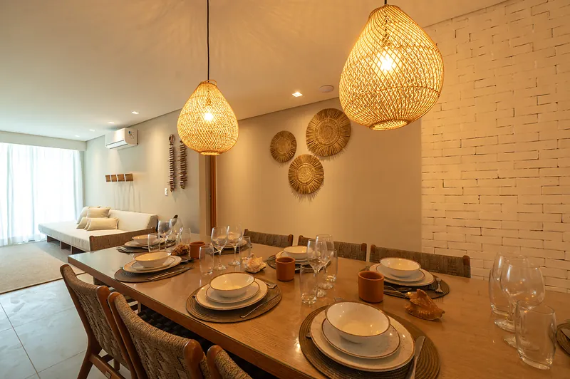Sala de jantar de apartamento conceito, com mesa posta e tijolo aparente branco.